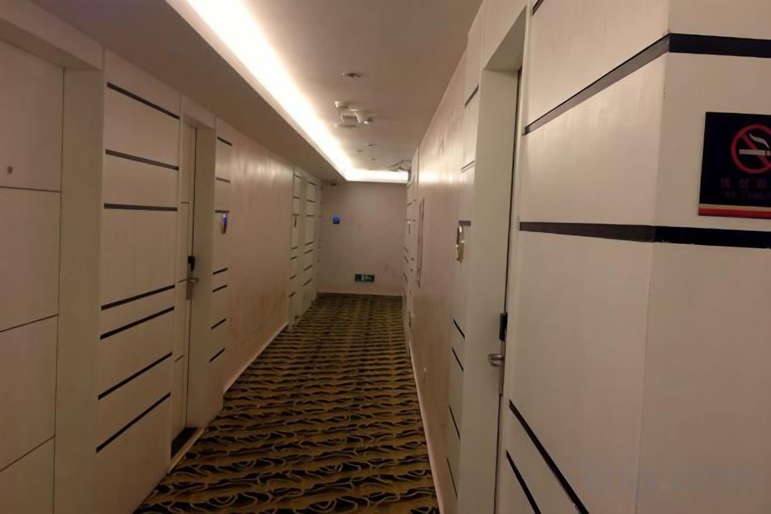 A hotel corridor with lockers, a patterned carpet, and a no-smoking sign.