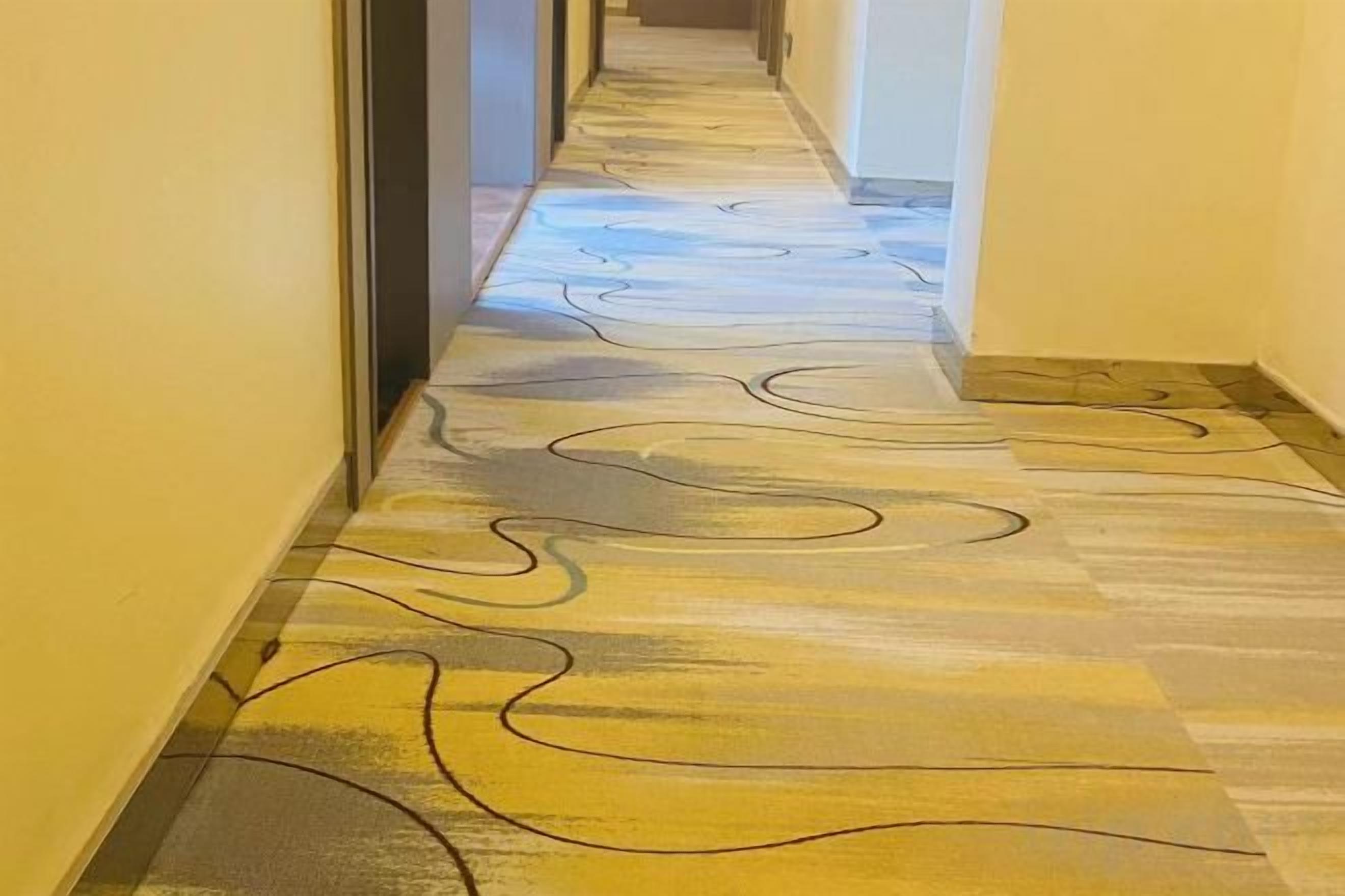 A hallway with patterned flooring and a door on the left.