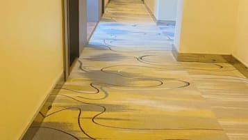 A hallway with patterned flooring and a door on the left.