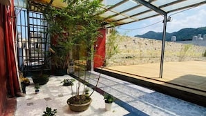 Une terrasse sur le toit agrémentée de plantes en pot, dotée d’une structure vitrée et offrant une vue sur les environs.