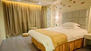 Une chambre d’hôtel avec un grand lit, une table de chevet, un petit tabouret et un rideau.