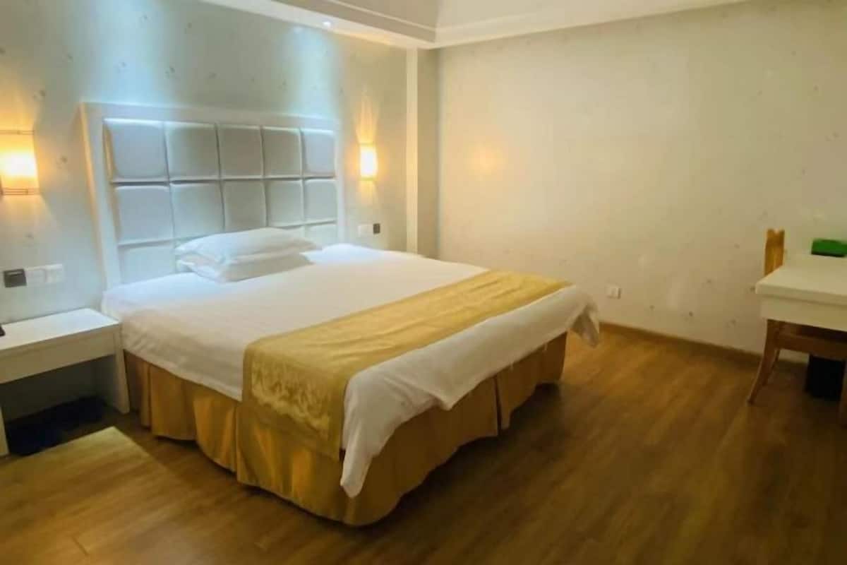 A hotel room with a large bed, bedside tables, a desk, and a chair.