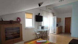 A bedroom with a bed, a desk, a television, and a kitchenette. - Apartments Vala - One Bedroom Apartment with Balcony and Sea View A4 (Vinisce)