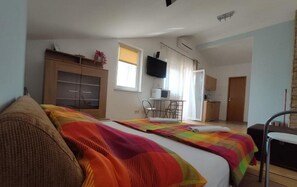 Une chambre à coucher avec un lit, un bureau, une télévision et une porte.