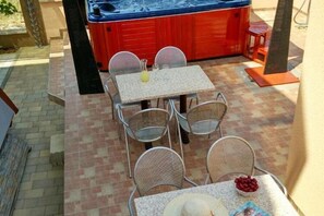 Un espace patio avec une table et des chaises, un jacuzzi et un sol en briques.