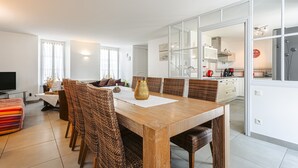 Un salon moderne avec une table à manger en bois, des chaises en osier, un téléviseur à écran plat et un canapé.