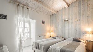 Une chambre avec deux lits, des murs recouverts de panneaux en bois, une fenêtre avec des rideaux et des lampes de chevet.