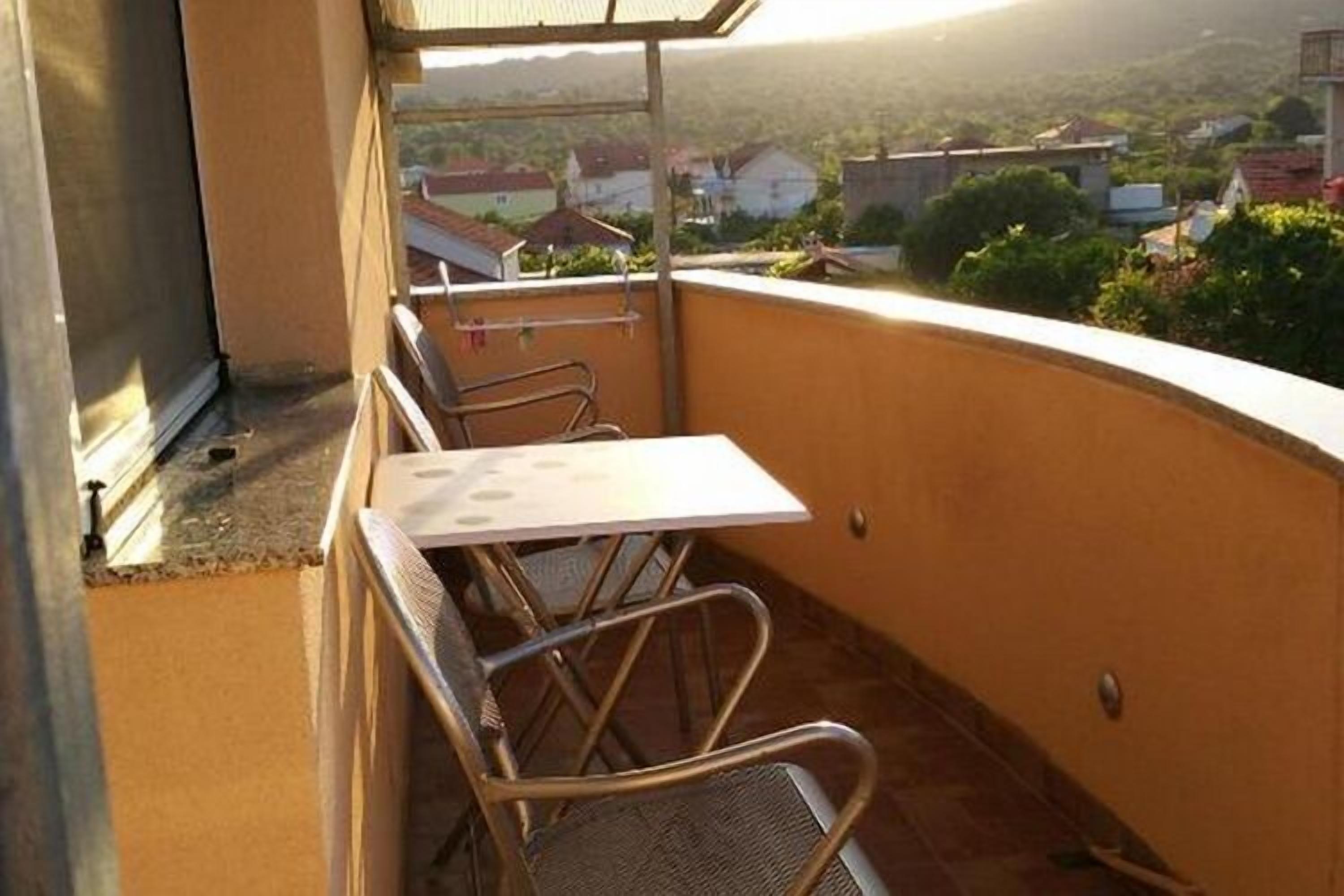 Ein Balkon mit Tisch und Stühlen, mit Blick auf eine Wohngegend.