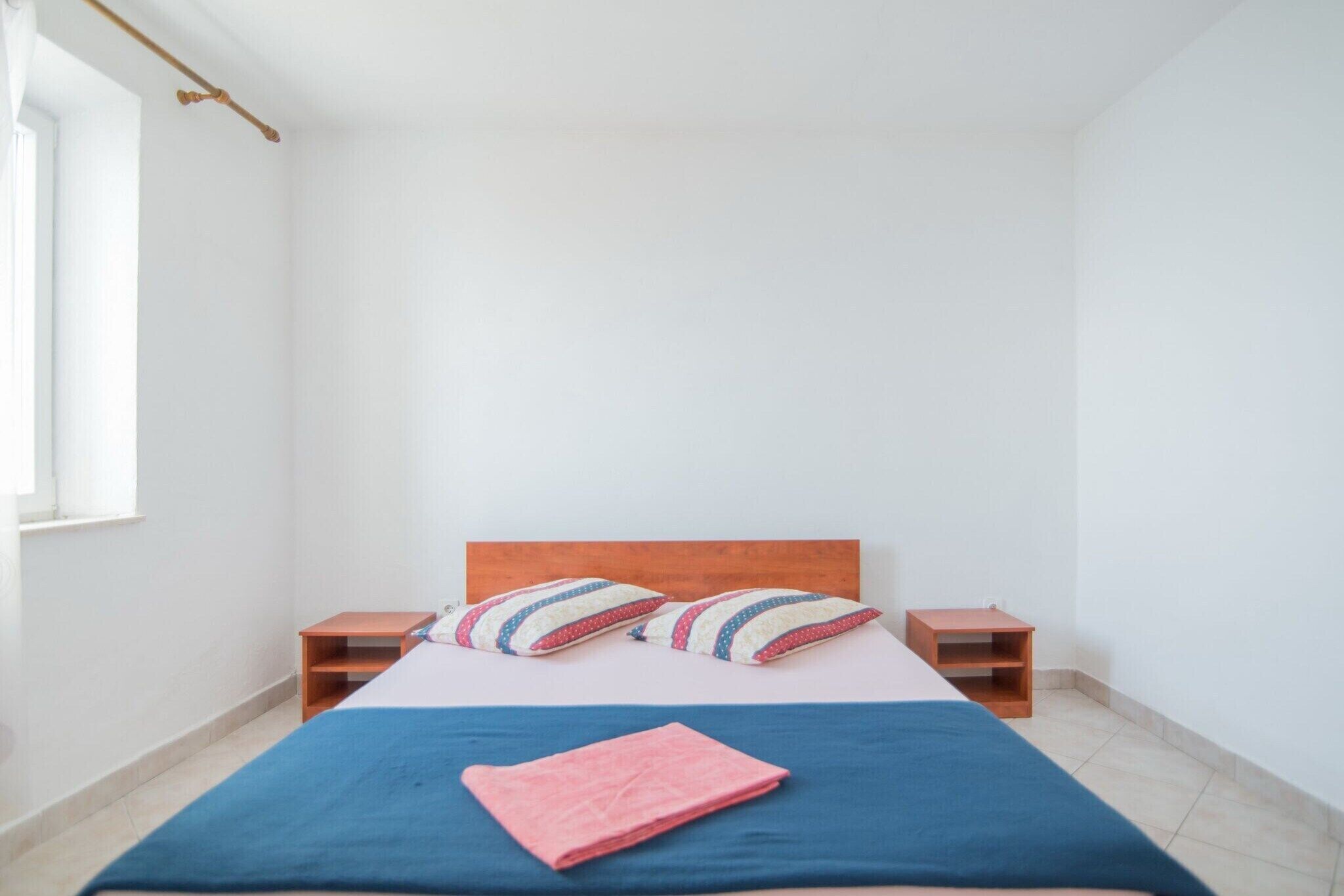 A simple, clean room with a bed, two nightstands, and a window.