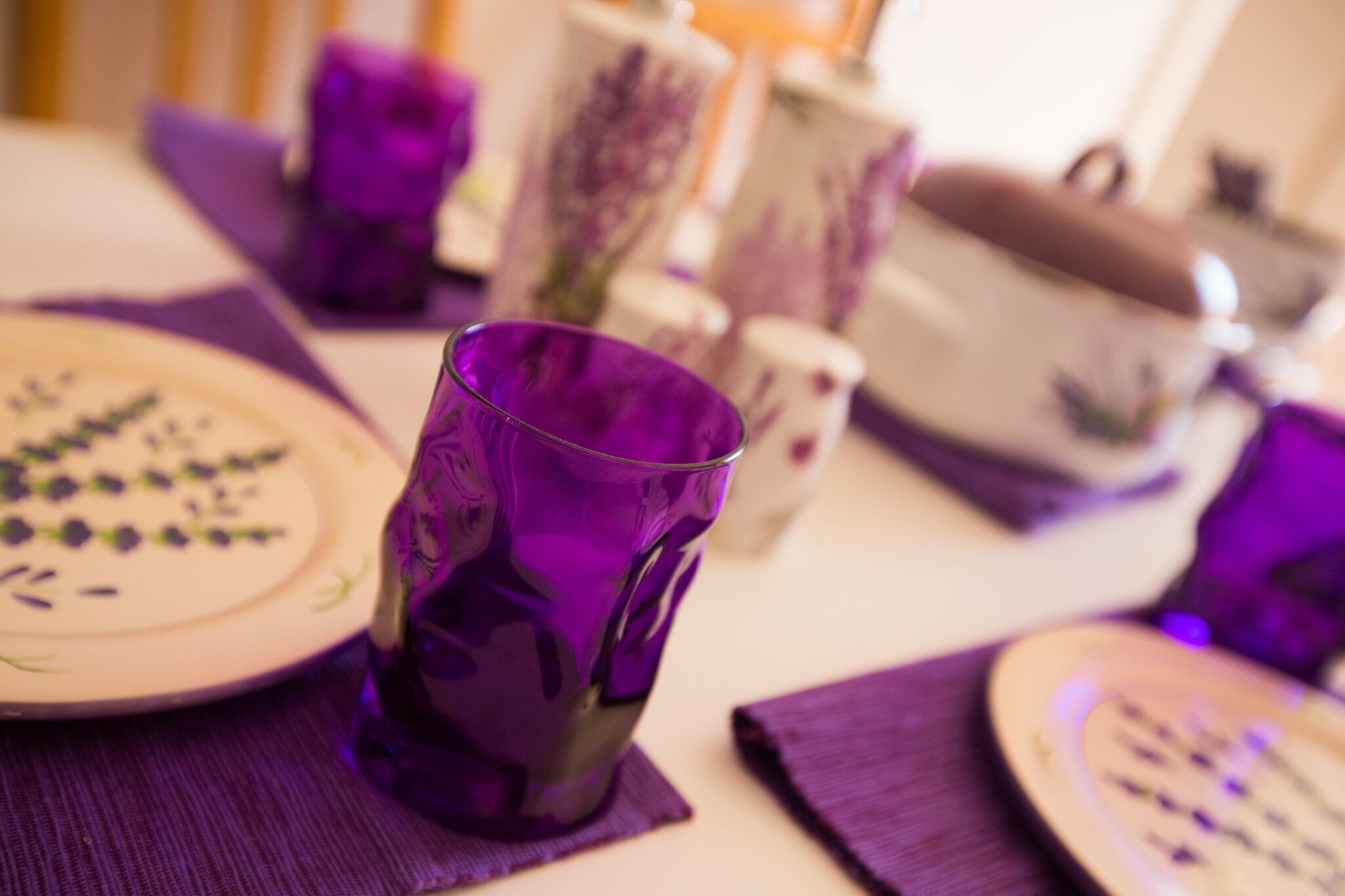 A table set with purple glassware, plates, and napkins, suggesting a themed dining experience.