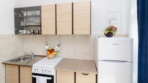 A compact kitchen with a built-in stove, a sink, and a refrigerator.