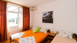 A bedroom with two beds, a window with curtains, a wall-mounted air conditioner, and a painting. - Apartments Mamma Mia - Comfort One Bedroom Apartment with Terrace (Mlini)
