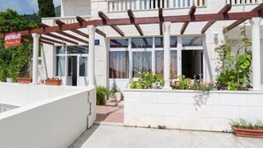 A white building with a covered patio area, a sign indicating apartments, and potted plants. - Apartments Mamma Mia - Comfort One Bedroom Apartment with Terrace (Mlini)