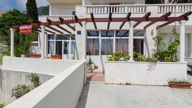 A building with a covered entrance, potted plants, and a sign indicating it is an apartment complex. - Apartments Mamma Mia - Comfort One Bedroom Apartment with Terrace (Mlini)