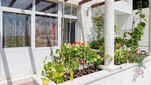 A white building with large windows and a garden area with various plants and flowers. - Apartments Mamma Mia - Comfort One Bedroom Apartment with Terrace (Mlini)