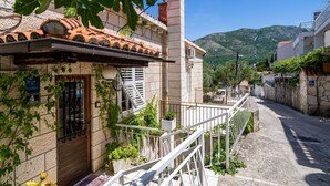 A narrow street with traditional stone buildings, a visible staircase, and a clear view of a mountain in the background. - Apartments & Rooms Mara & Petrunjela - One Bedroom Apartment with Balcony and Sea View (Cavtat)