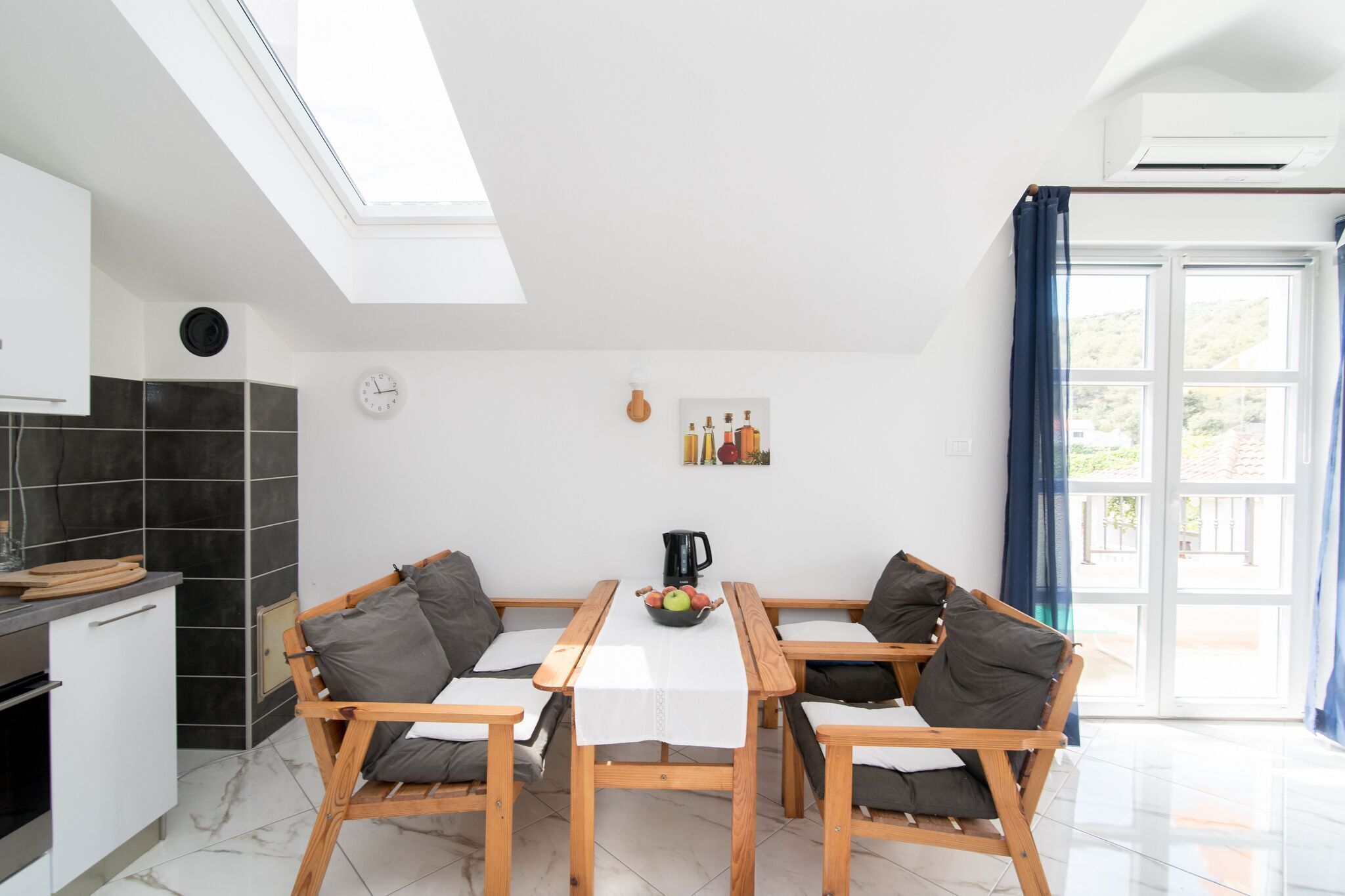 Een moderne keuken met een eethoek, met een dakraam, een klok en uitzicht op de omgeving.