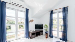 Una sala de estar moderna con un televisor de pantalla plana, un mueble de madera para entretenimiento y una planta en maceta.