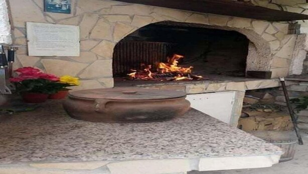 A stone fireplace with a fire burning inside, surrounded by a stone wall and a wooden shelf above. - Apartments Marija - One Bedroom Apartment with Balcony and Sea View (Žuti A2) (Pirovac)