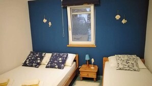 A bedroom with two beds, a window, and a nightstand with a lamp.
