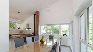 Een moderne keuken met een eethoek, grote ramen en een bakstenen schoorsteen.