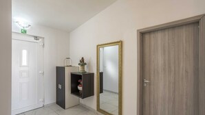 Un pasillo con una puerta blanca, un mueble negro con espejo y una puerta de madera.