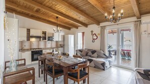 Amplia sala de estar con techo de madera, mesa de comedor preparada para cuatro personas y sofá con diseño geométrico.