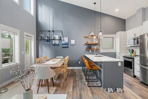 Una cocina moderna con una isla central, electrodomésticos de acero inoxidable y un comedor con mesa y sillas de madera.