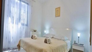 A bedroom with a bed, two bedside tables, a nightstand, and a wall-mounted picture. - Apartments Lenka - One Bedroom Apartment with Balcony and Center View A3 (Sutivan)