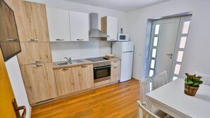 A modern kitchen with wooden cabinets, a built-in oven, a microwave, and a sink. - Apartments Lenka - Two Bedroom Apartment with Garden Terrace A4 (Sutivan)