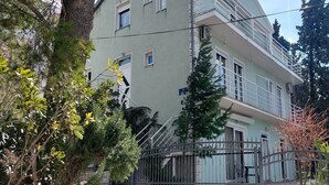 Un immeuble à plusieurs étages doté de balcons, entouré d’arbres et d’une clôture en métal.