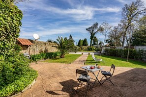 Une terrasse avec une table et des chaises, une antenne parabolique et un mur en pierre.