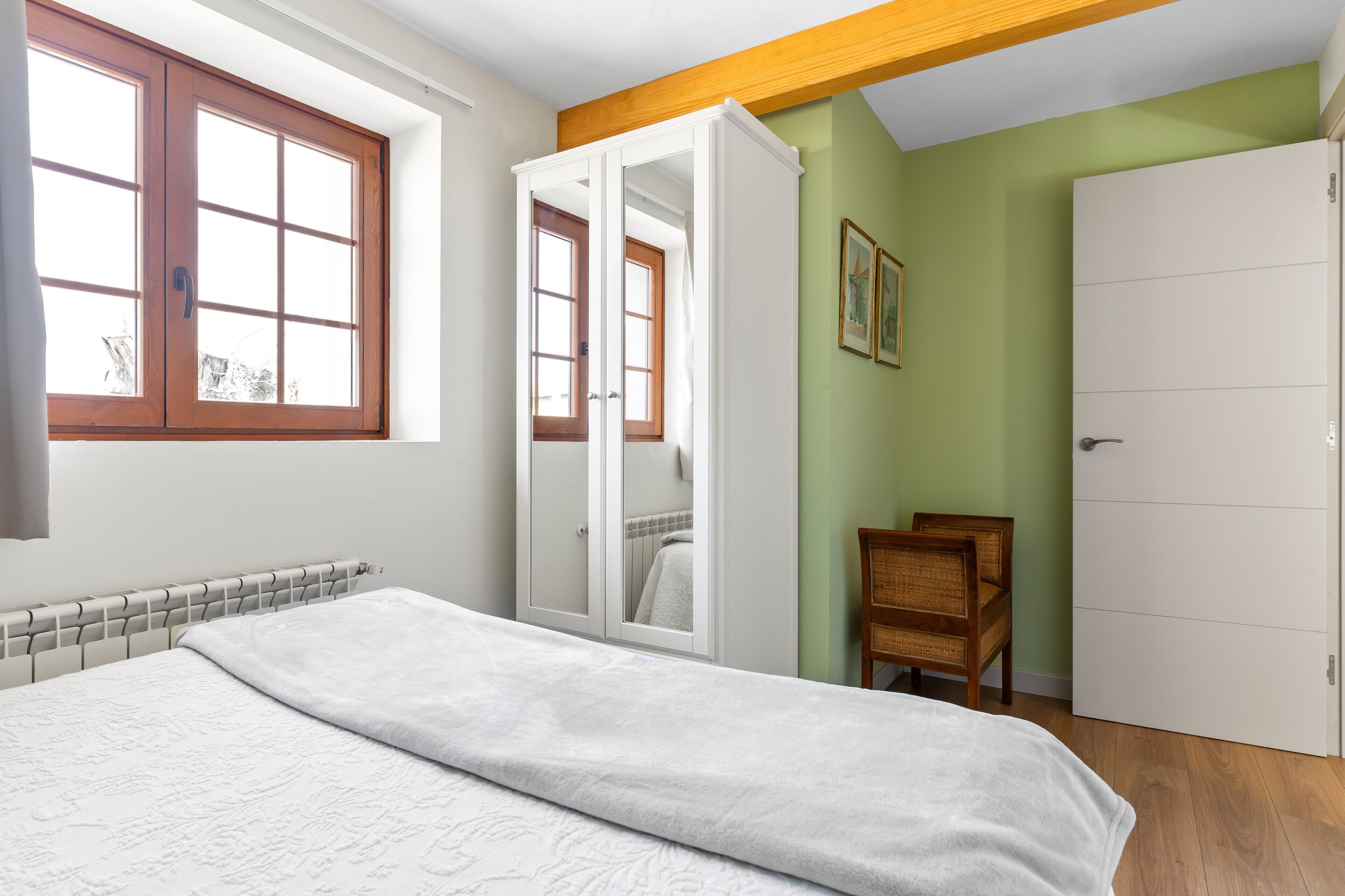 A bedroom with a bed, a wardrobe, a chair, and a window.