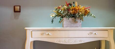 Una consola blanca con un jarrón de flores y una decoración floral blanca.