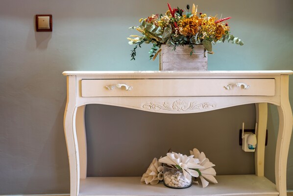 Una consola blanca con un jarrón de flores y una decoración floral blanca.