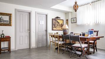 A dining area with a wooden table, chairs, a lamp, and framed pictures on the wall.