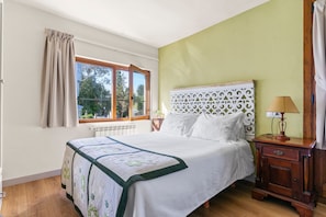 Une chambre à coucher avec un lit, une fenêtre, une table de chevet et une lampe.