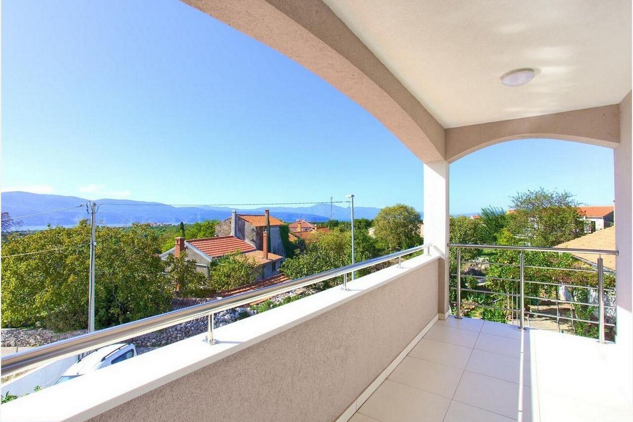 A balcony with a view of a town and mountains.