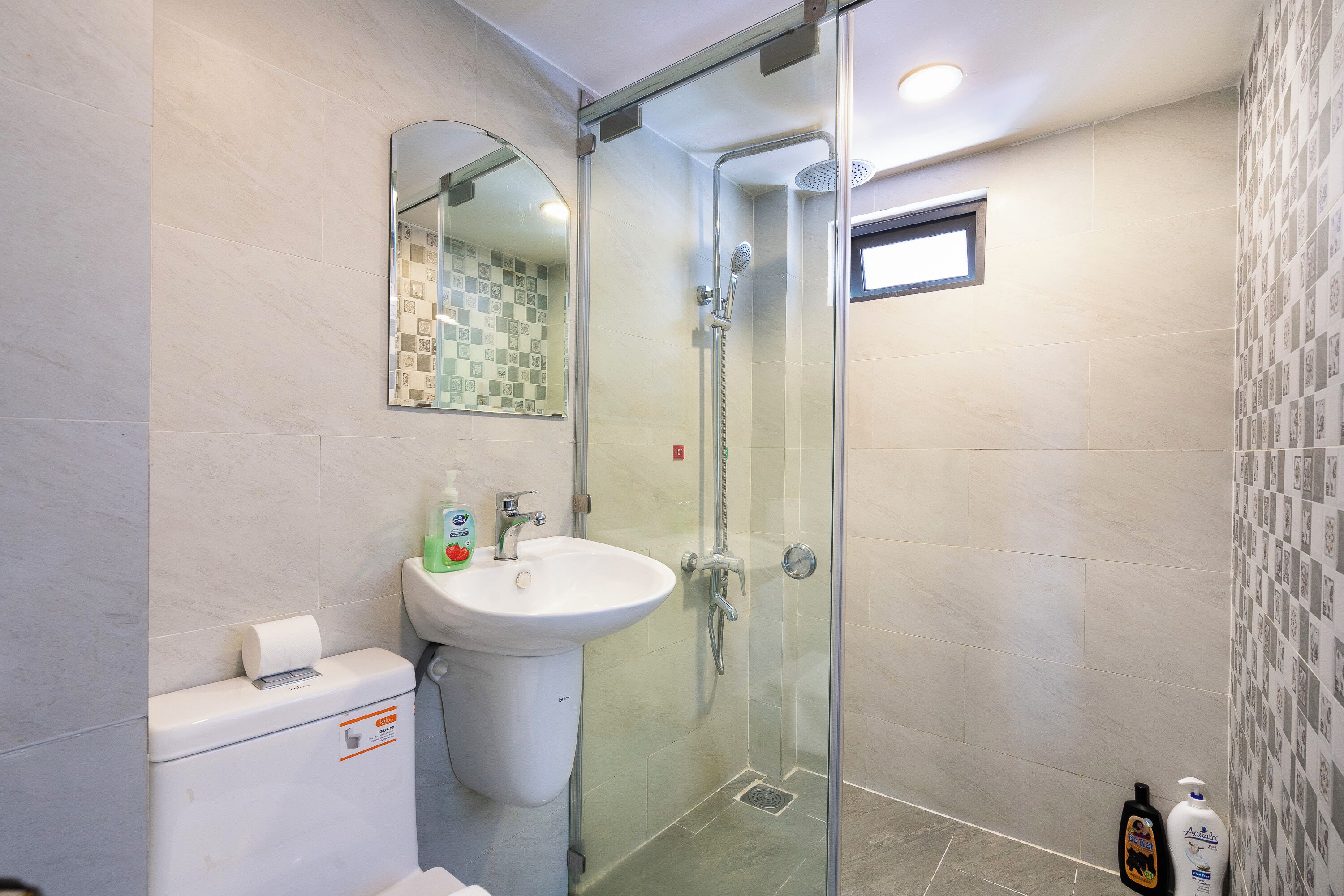 Une salle de bain avec une douche à parois de verre, un lavabo et des toilettes.