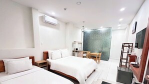 Een hotelkamer met twee bedden, een bureau, een stoel en een kleine kitchenette.