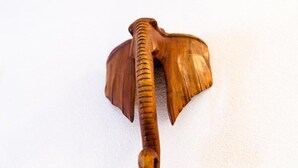 Un objeto de madera que parece un mazo, con mango texturizado y cabeza redondeada.