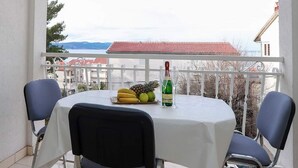 A balcony with a table set for two, featuring a bottle of champagne, a pineapple, and a plate of bananas and apples. - Apartments Pezo - Superior Studio with Balcony and Sea View (Baška Voda)