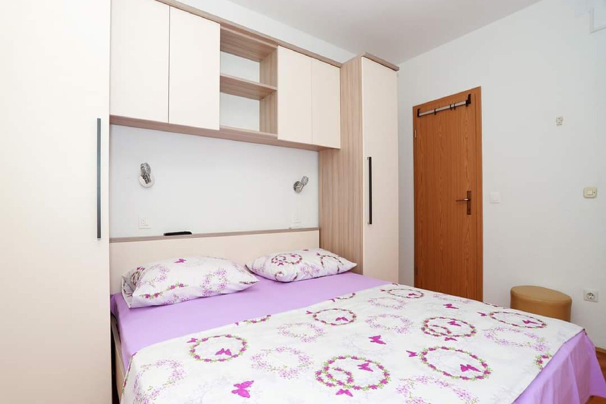 A bedroom with a bed, a wardrobe, and a door.