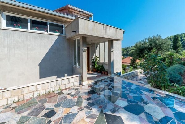 Une maison moderne dotée d’une piscine carrelée et d’un patio couvert.