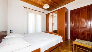 Une chambre avec un plafond en bois, un lit avec une literie blanche, un banc en bois et une armoire.