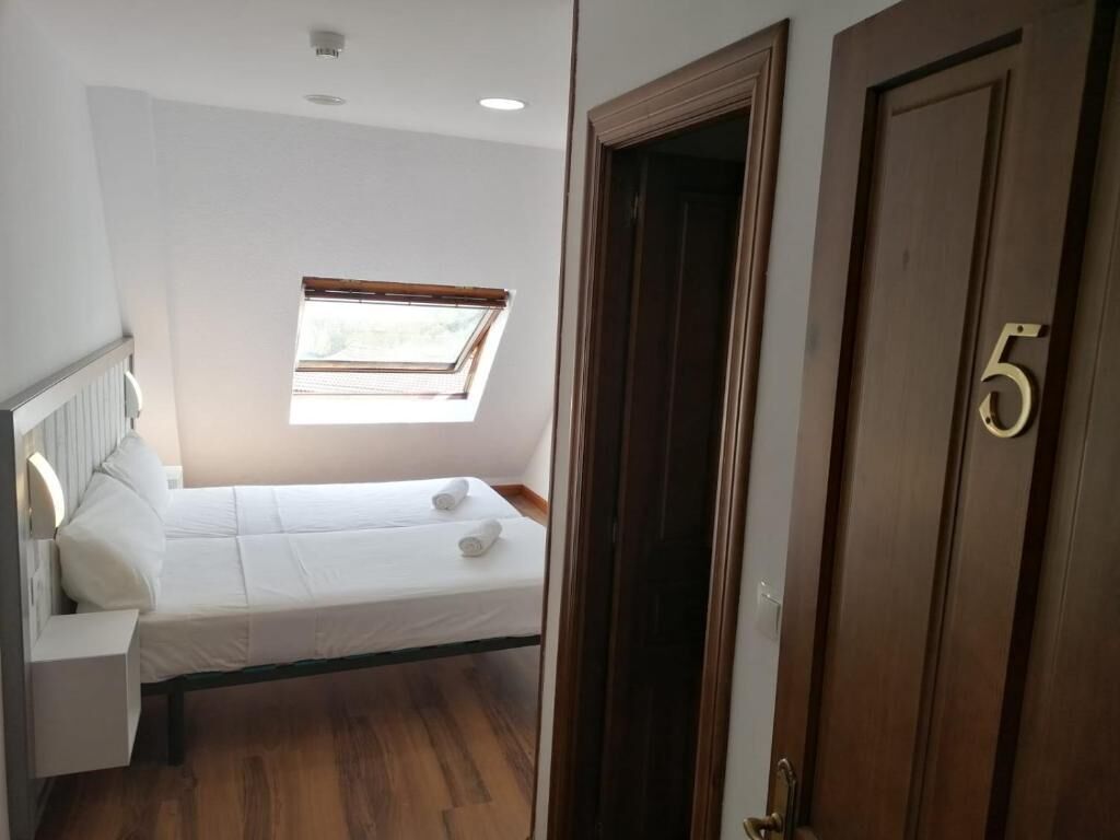 Una habitación pequeña con una cama, un ventanal y una puerta con el número 5.
