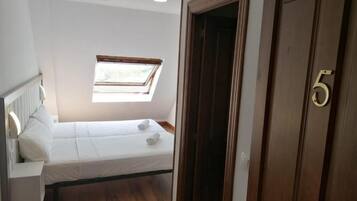 Una habitación pequeña con una cama, un ventanal y una puerta con el número 5.