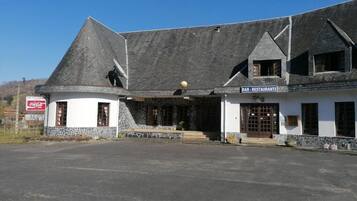 A building with a stone facade, a sloped roof, and a sign indicating a bar and restaurant.