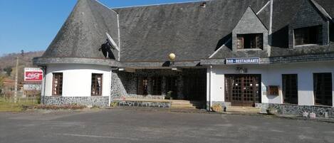 A building with a stone facade, a sloped roof, and a sign indicating a bar and restaurant.