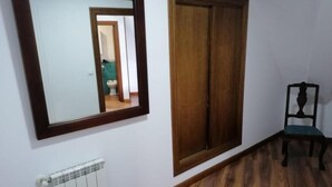 Une pièce avec un plancher en bois, un radiateur, une armoire en bois et une chaise.